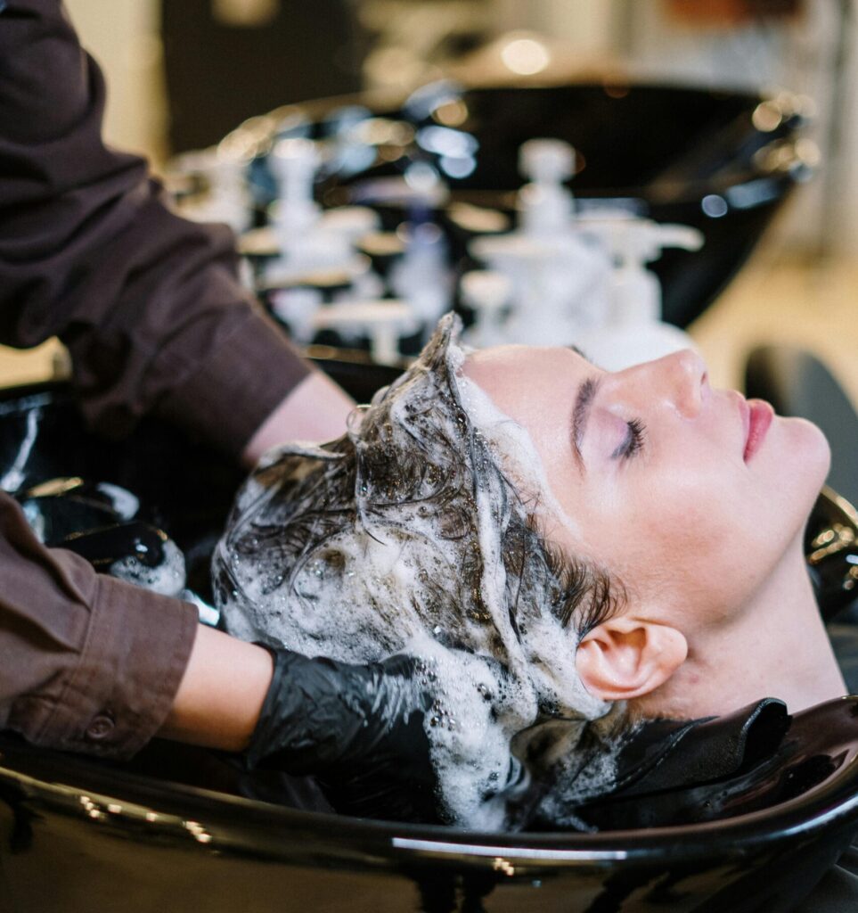Professional hair stylist washing woman's hair in a modern salon setting.