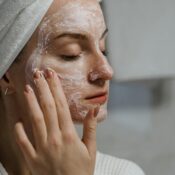 A woman applying a clay mask as part of her self-care beauty regimen indoors.